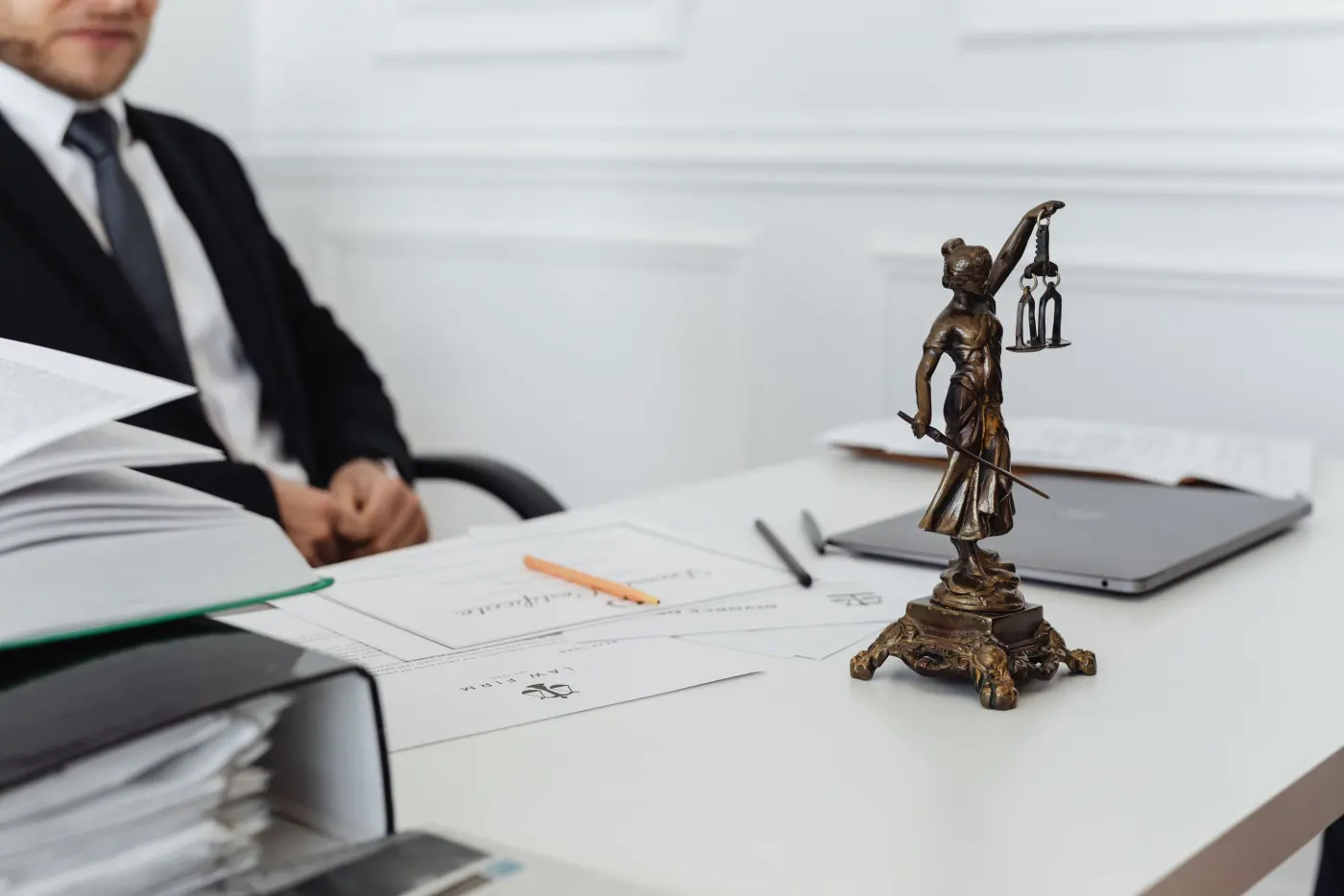 A lawyer’s desk with a statue of Lady Justice, papers and a laptop